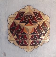 a decorative wall hanging on the side of a building with geometric designs in gold, red and black