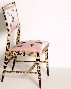 a pink chair with black and white designs on it's back, against a white wall