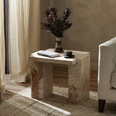 a small table with a vase on it next to a couch and chair in a living room