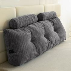 a gray pillow sitting on top of a white couch