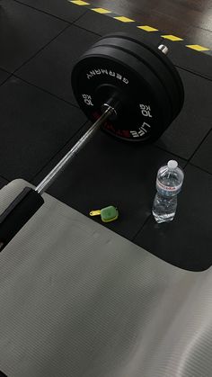 a barbell weight machine with a bottle of water on the ground next to it