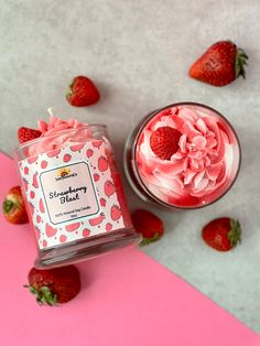 a jar of strawberry butter next to some strawberries on a pink and white surface