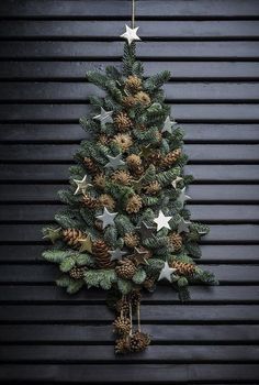 a small christmas tree with pine cones and stars hanging from it's sides, against a black background