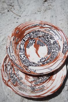 two brown and white plates sitting on top of a cement floor next to each other