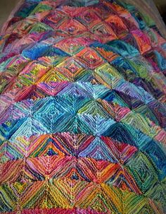 a multicolored crocheted blanket sitting on top of a bed