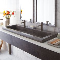 a bathroom sink sitting under two mirrors in front of a counter with flowers on it