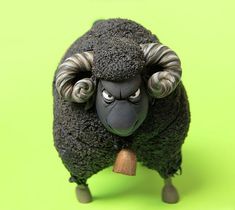 a black sheep with horns and big ears on it's head is standing in front of a green background