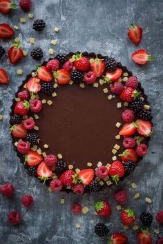 a chocolate tart topped with strawberries and blackberries on top of a table