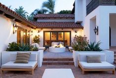 an outdoor living area with white furniture and potted plants