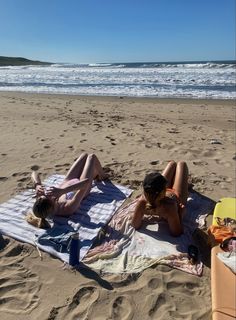 two people laying on a towel at the beach