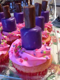 cupcakes with purple frosting and chocolate sticks sticking out of them on a clear platter