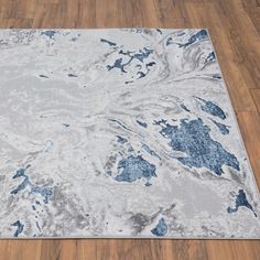 a white and blue area rug with wood flooring in the background on top of a hard wood floor