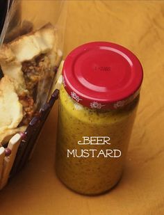 a bottle of beer next to a sandwich in a plastic container on a wooden table