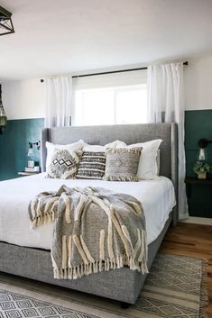 a bedroom with a bed, rugs and pillows on the floor in front of a window