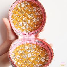 a hand is holding an orange and white box with flowers on it's sides