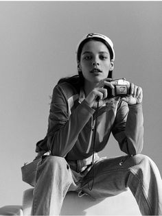 a woman sitting on top of a white object holding a camera