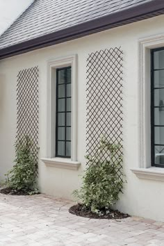 a white house with three windows and some plants