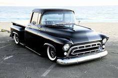 an old black pickup truck parked on the beach