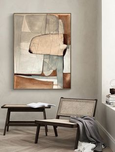 an abstract painting hangs on the wall next to a chair and coffee table in a living room