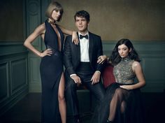 three people in formal wear sitting on a red chair with one person wearing a tuxedo