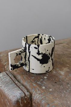 a white and black cup sitting on top of a wooden table