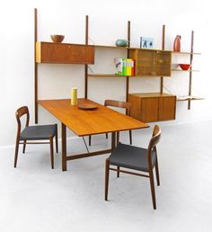 a wooden table with two chairs next to it and shelves on the wall behind it