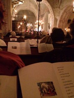 several people are sitting in the pews with open books on their laps, and one person is reading