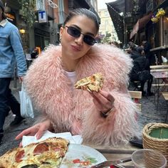 a woman sitting at a table eating pizza