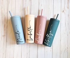 three personalized tumblers with straws in them sitting on a wooden table next to each other