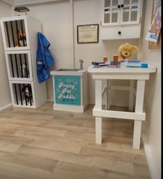 a teddy bear is sitting on a table in a room with white walls and wooden floors