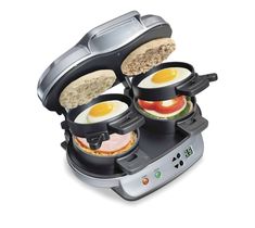 an electric breakfast sandwich maker with eggs, ham and tomato slices in the trays