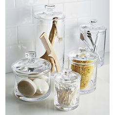 three glass containers with lids and spoons on a counter