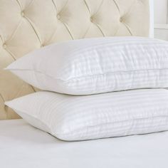 two pillows stacked on top of each other in front of a white bed headboard