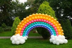 an arch made out of balloons in the shape of a rainbow with clouds on it