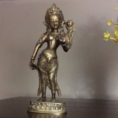 a gold statue is sitting on a table next to a vase with flowers in it