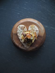 a heart shaped tortilla sitting on top of a wooden plate