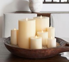 several lit candles sit in a bowl on a table