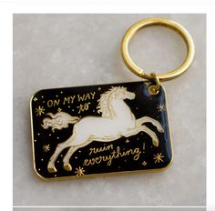 a black and gold keychain with a white horse on it's side