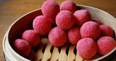 a wooden bowl filled with red sugar balls