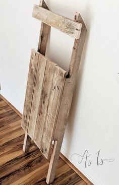 a wooden chair sitting on top of a hard wood floor next to a white wall