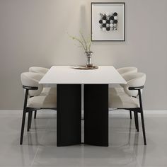 a white table with four chairs around it and a vase filled with flowers on top