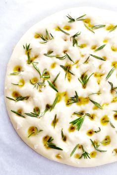 a pizza covered in cheese and herbs on top of a white paper towel with mountains in the background