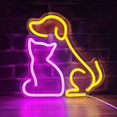 a neon cat sitting on top of a table next to a brick wall and purple light