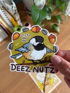 a hand holding up a sticker with a bird on it's back and the words deez nutz