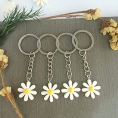 four key chains with daisies attached to them