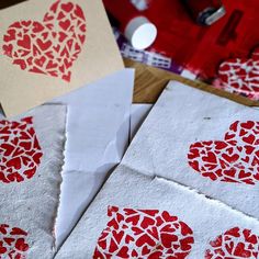 four pieces of paper with hearts cut out of them sitting on a table next to some crafting supplies