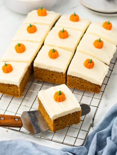 carrot cake with cream cheese frosting and mini pumpkins on top, sitting on a cooling rack