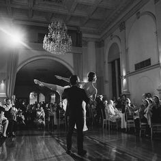 a bride and groom dance together in the middle of a large room full of people