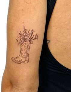 a woman's arm with a tattoo on it that has flowers in a boot