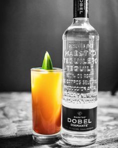 a bottle of alcohol next to a glass with an orange drink